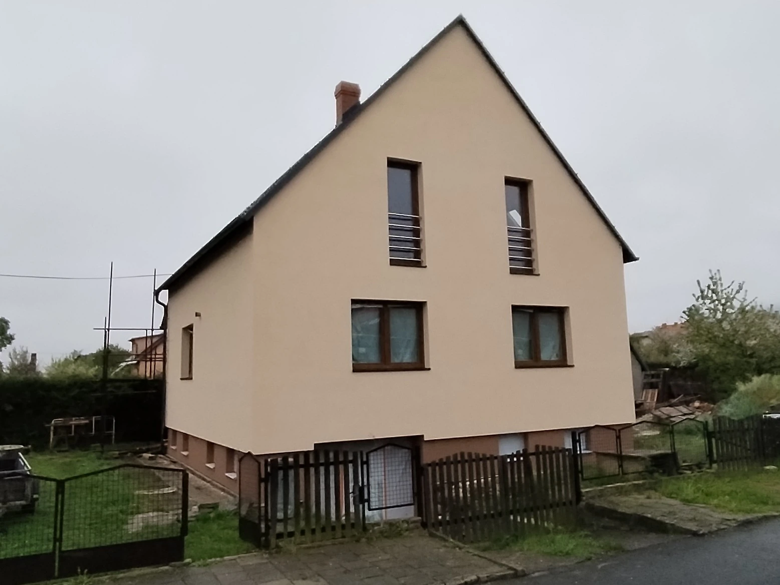 Rodinný dům ve Městě Albrechticích po renovaci, s novou světlou zateplenou fasádou a vyměněnými okny.