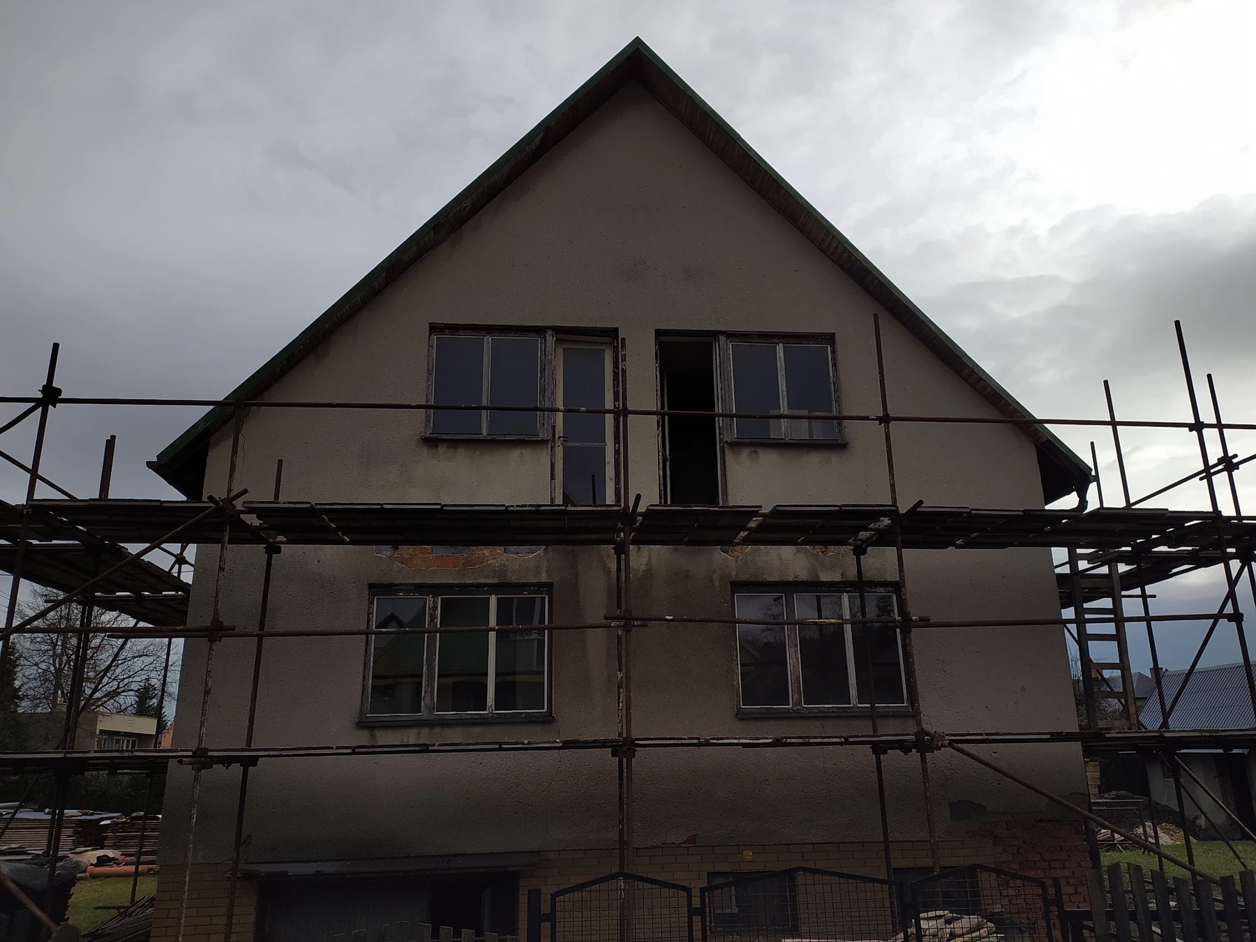 Rodinný dům ve Městě Albrechticích před renovací, s původní fasádou a okny, obklopený lešením.