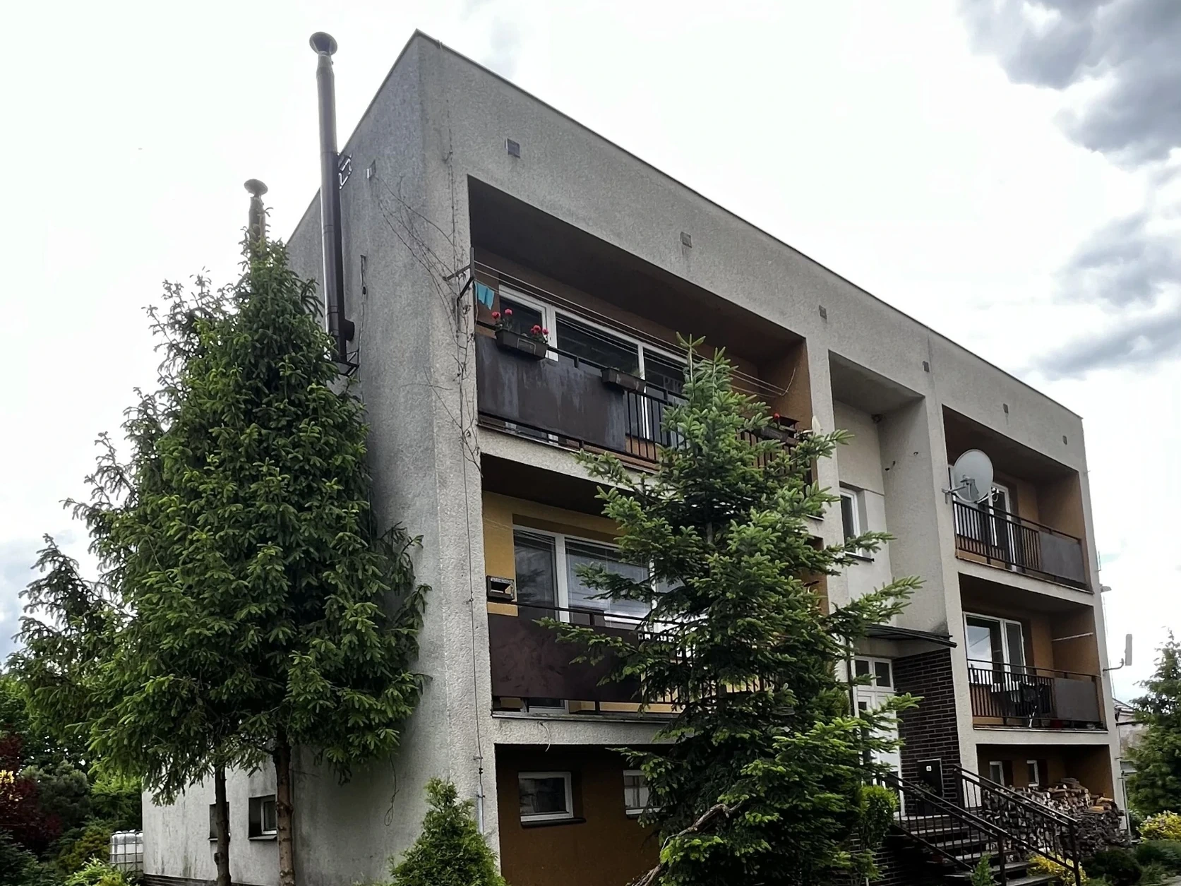 Bytový dům v Uhlířově před renovací, s původní fasádou a balkony.